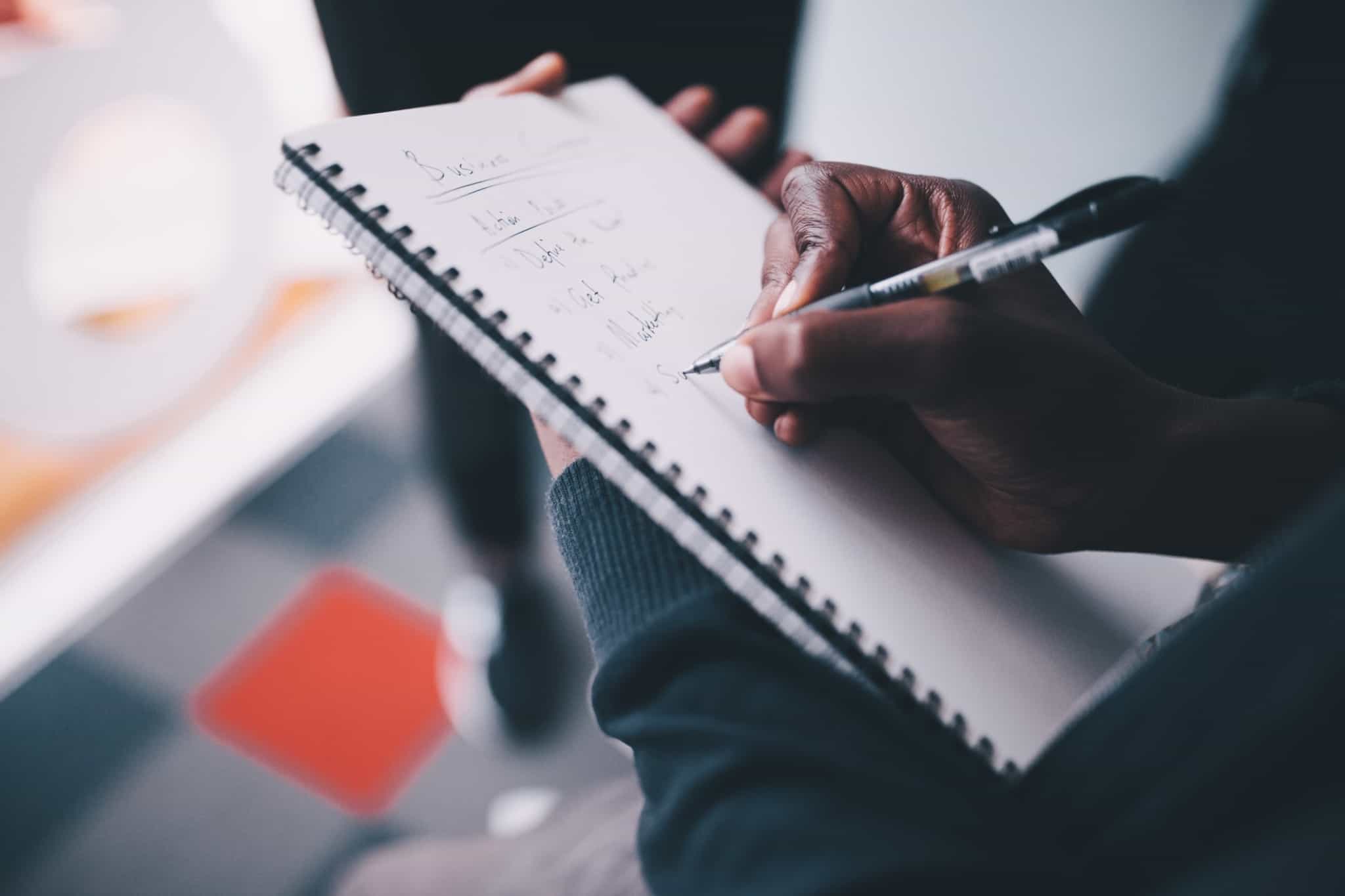 pessoa a escrever ideias de uma reunião