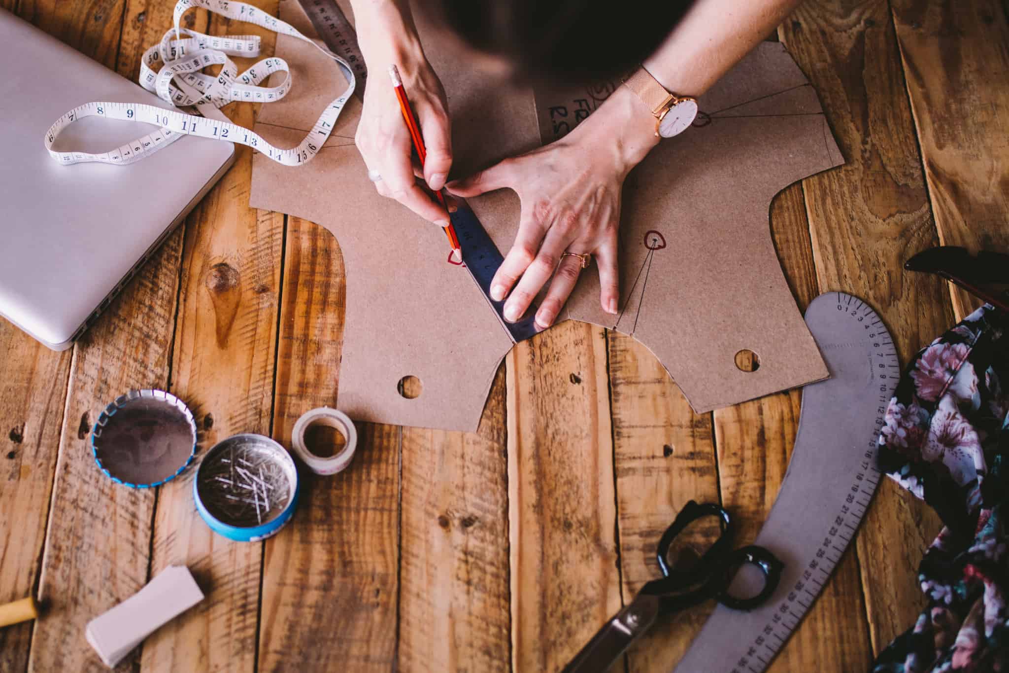 pessoa a riscar um molde castanho com um lapis vermelho