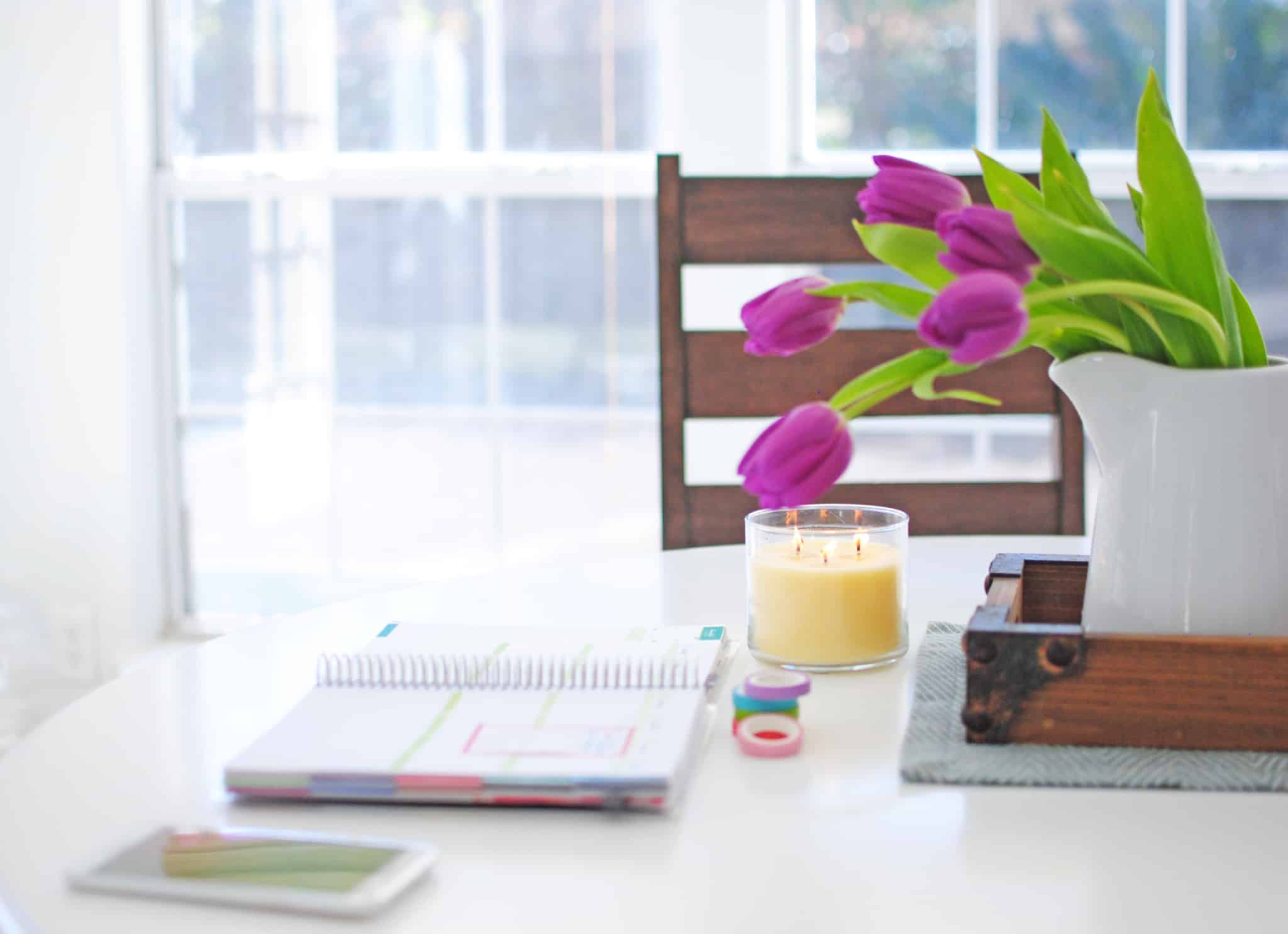 caderno em cima da mesa com vaso de flores ao lado