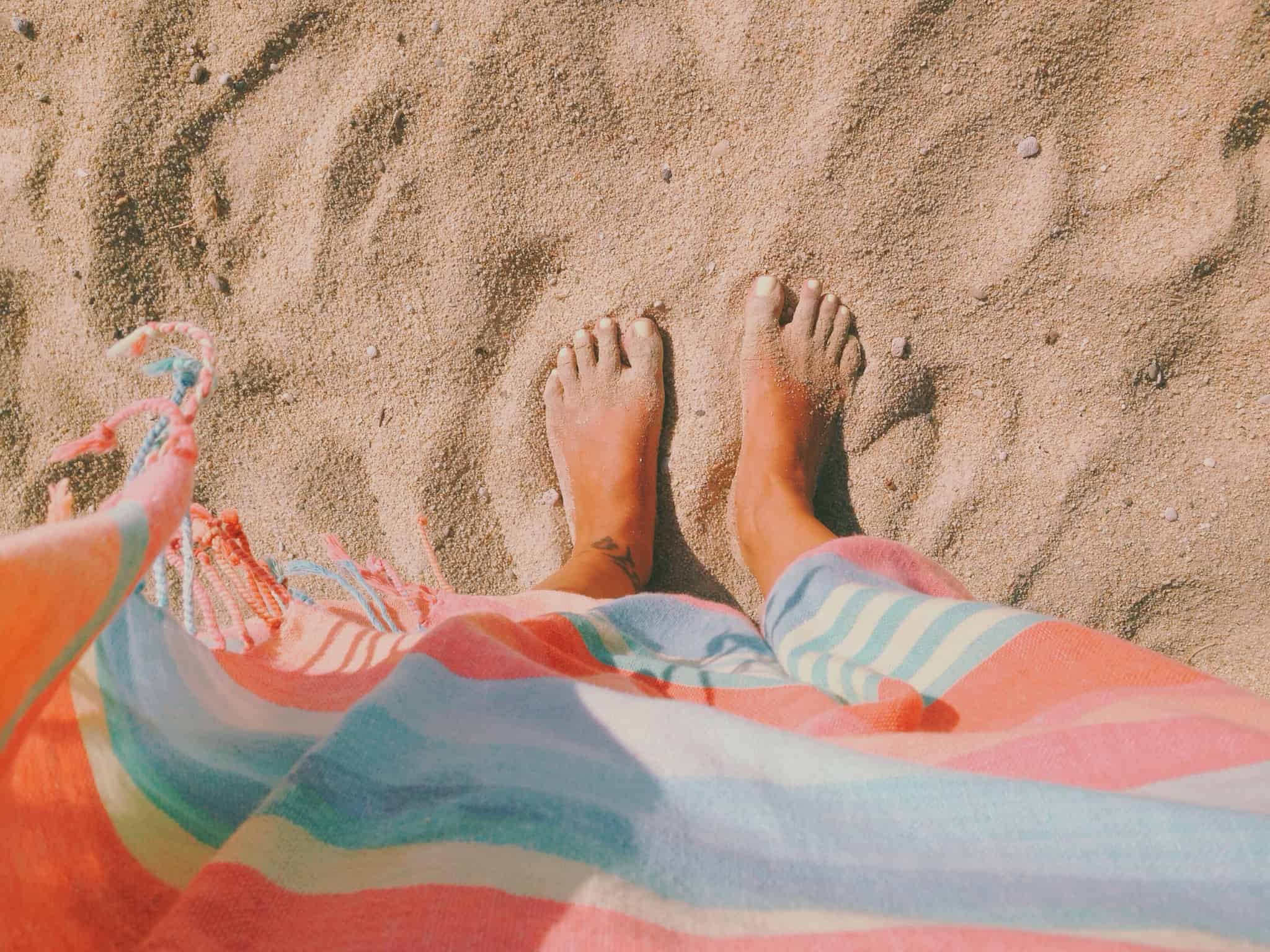 pessoa com os pés na areia da praia