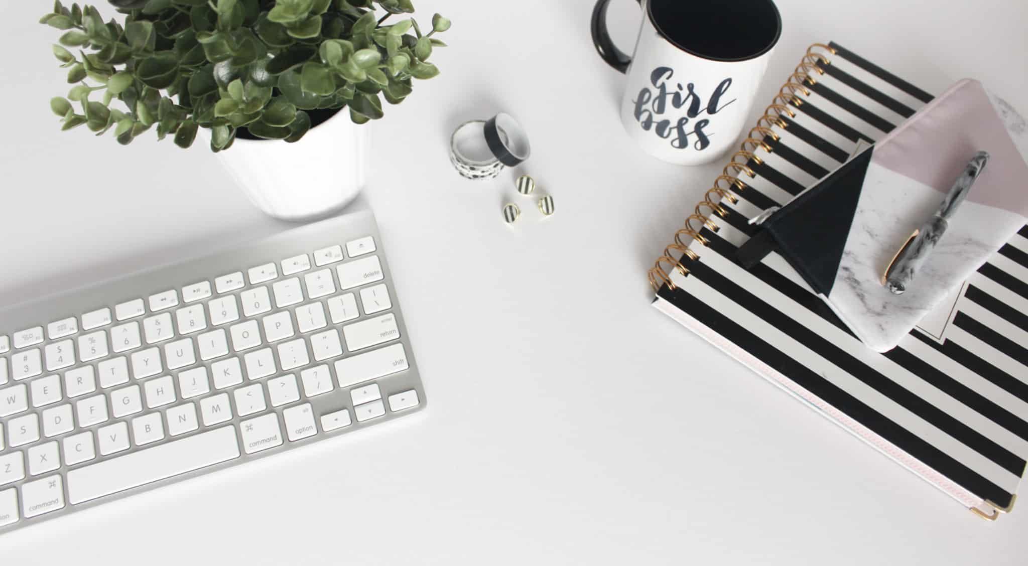 secretaria branca com caderno teclado mac e caneca branca