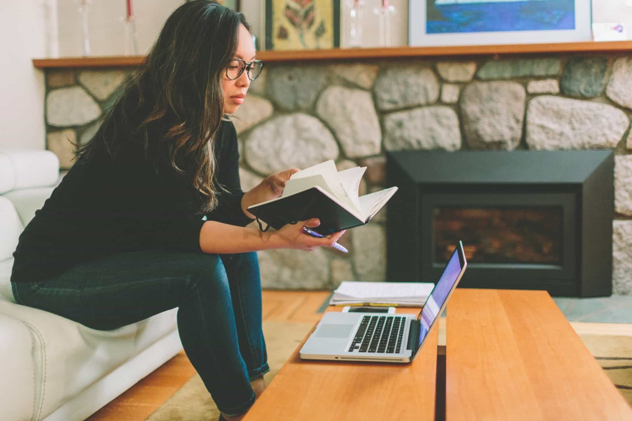 rapariga a trabalhar em casa sentada no sofá e com o computador em cima da mesa