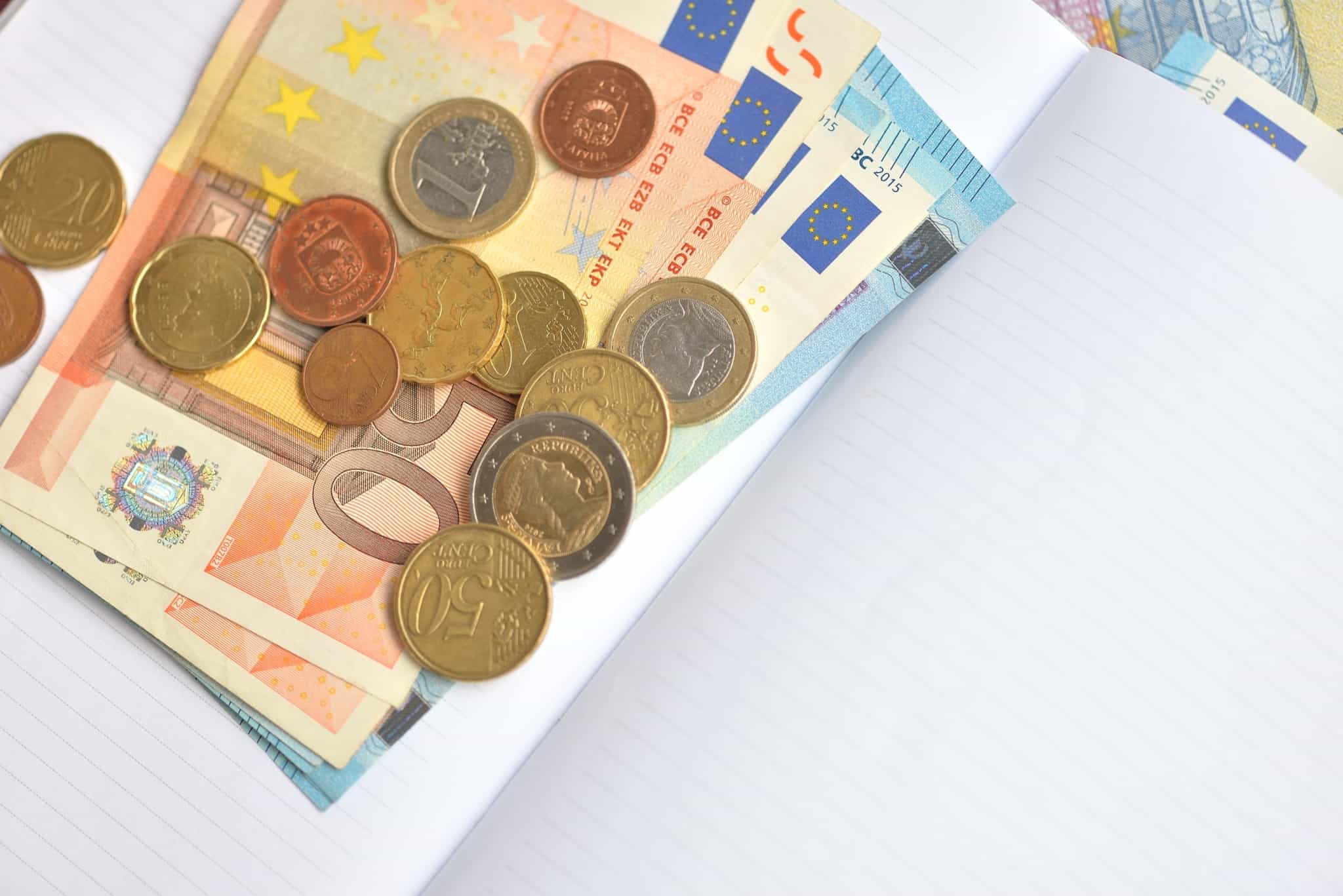 notas e moedas de euros dentro de um bloco de notas