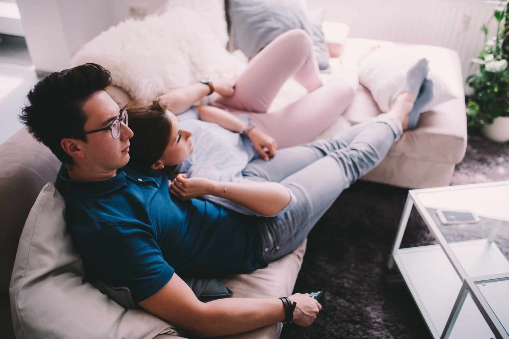 casal deitado no sofá a ver televisão