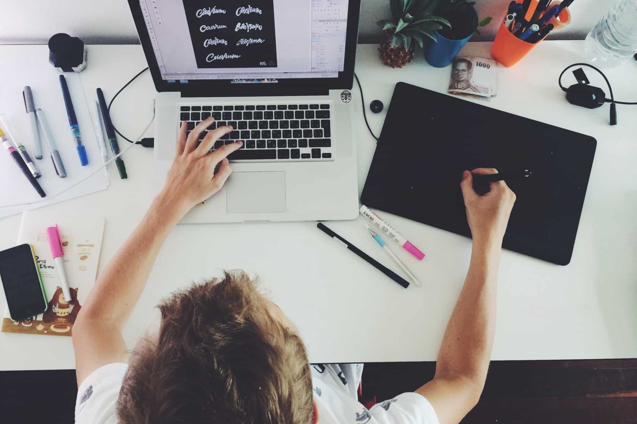 designer faz tipos de letras no portatil e com uma mesa gráfica