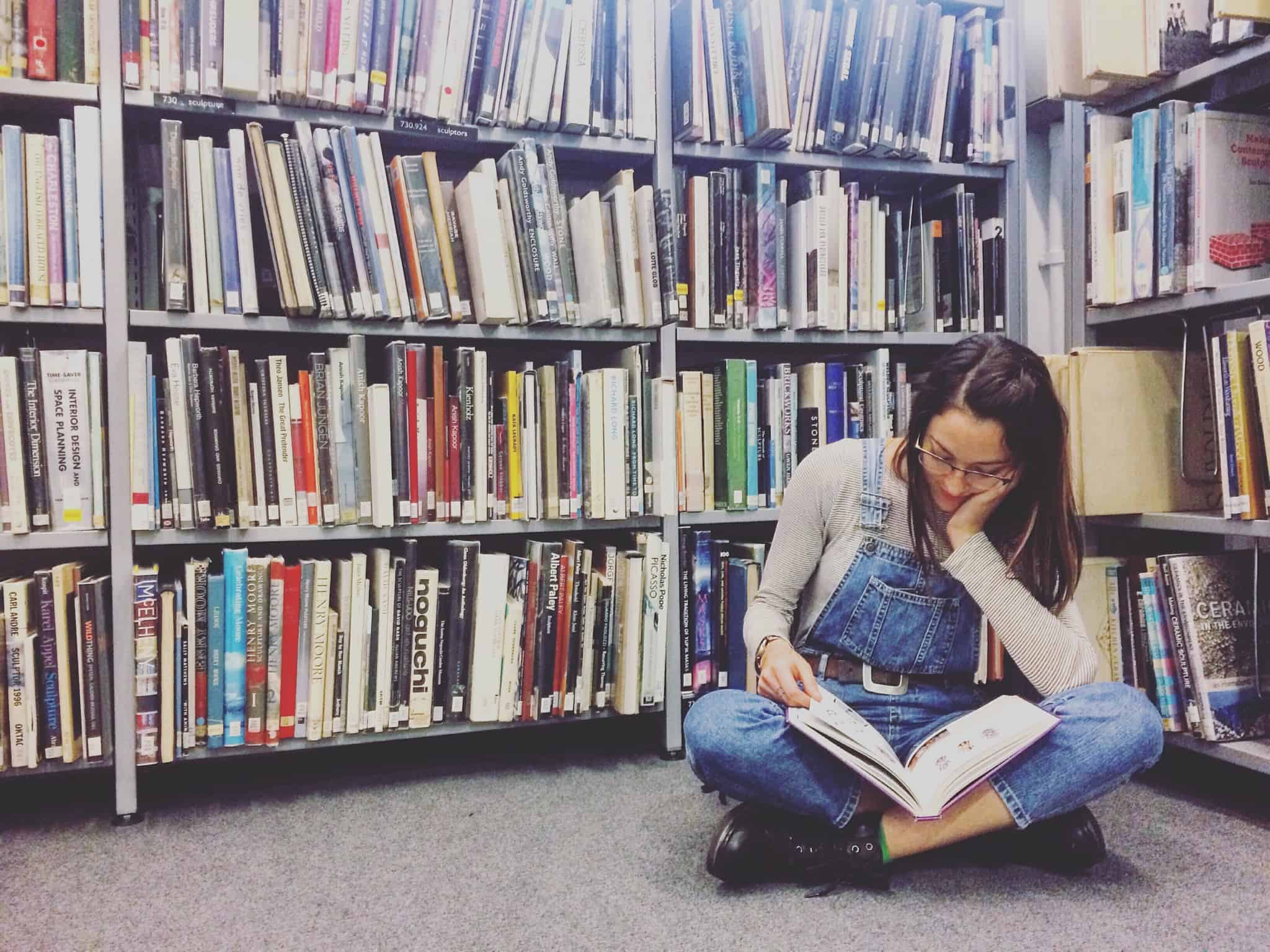 rapariga a ler no chão da biblioteca