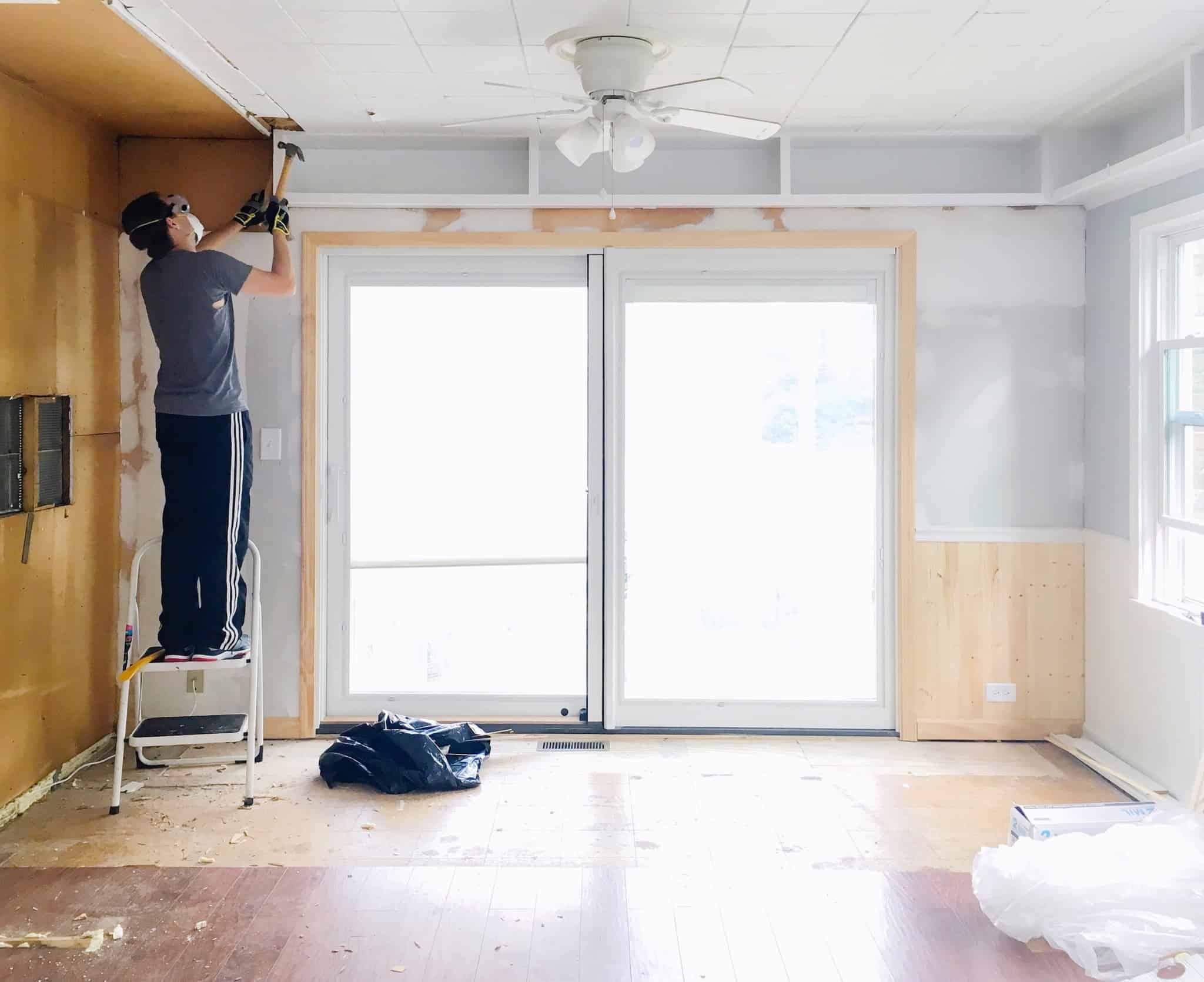 homem a fazer obras no tecto de uma sala