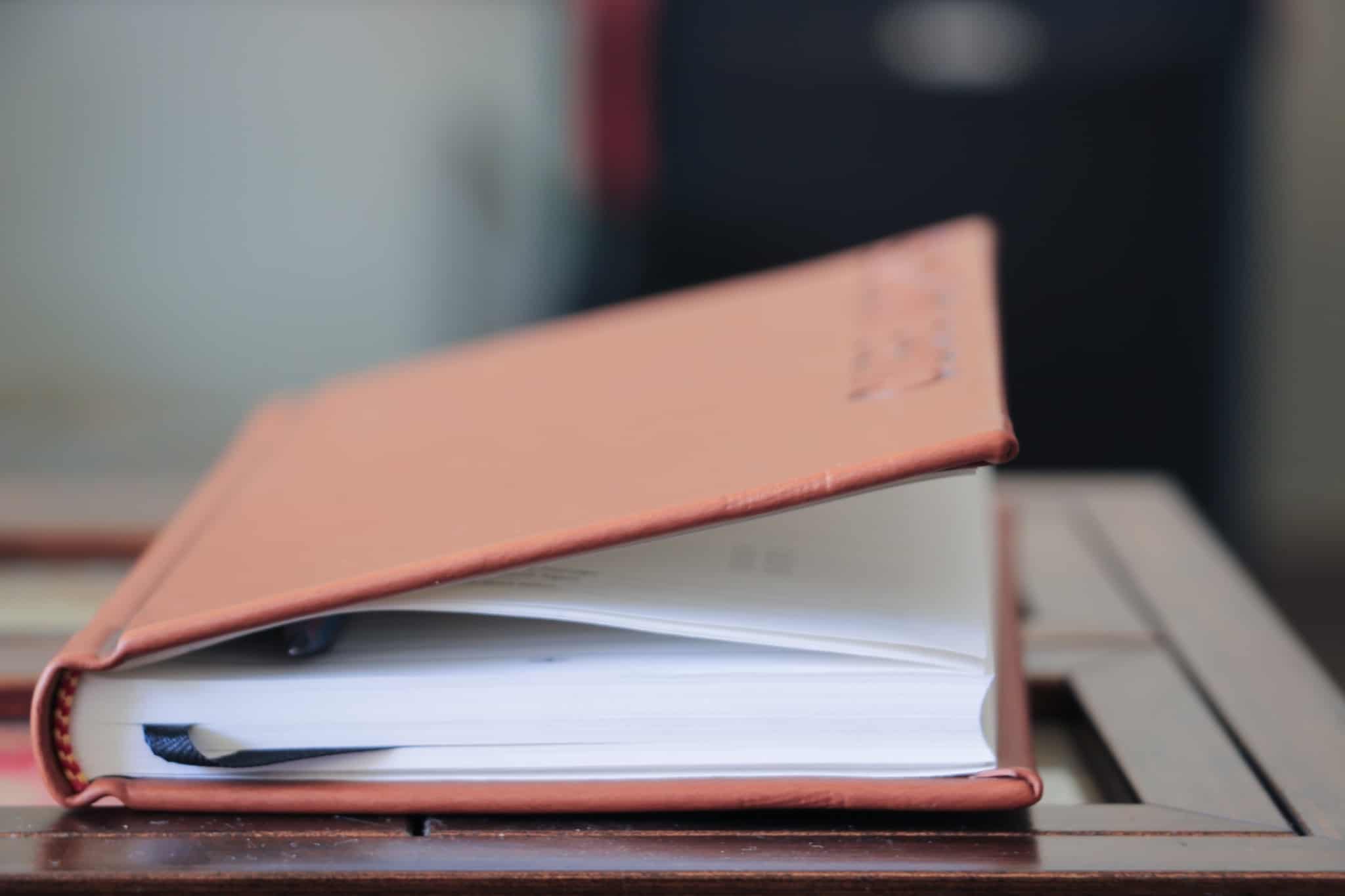 caderno cor de rosa com uma caneta no meio