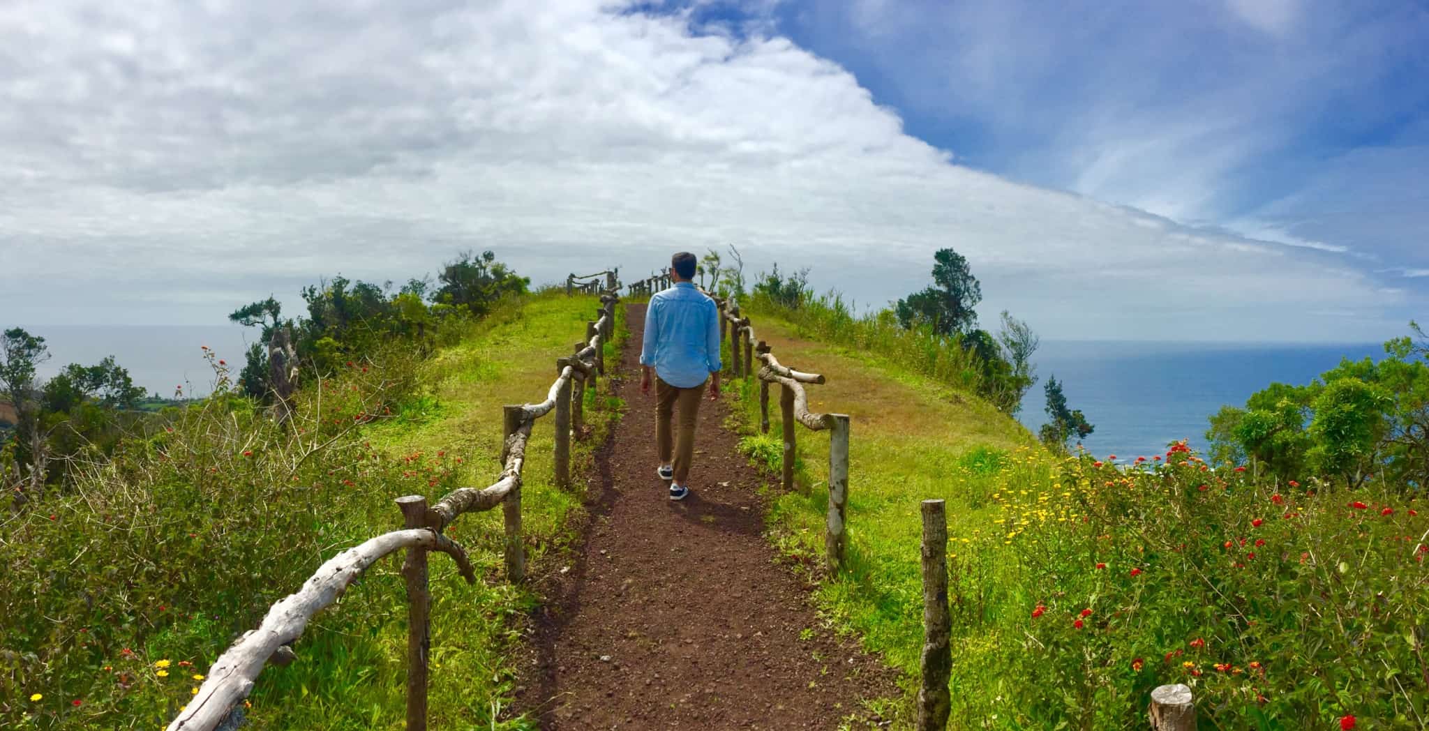 homem a passear num campo verde nos açores