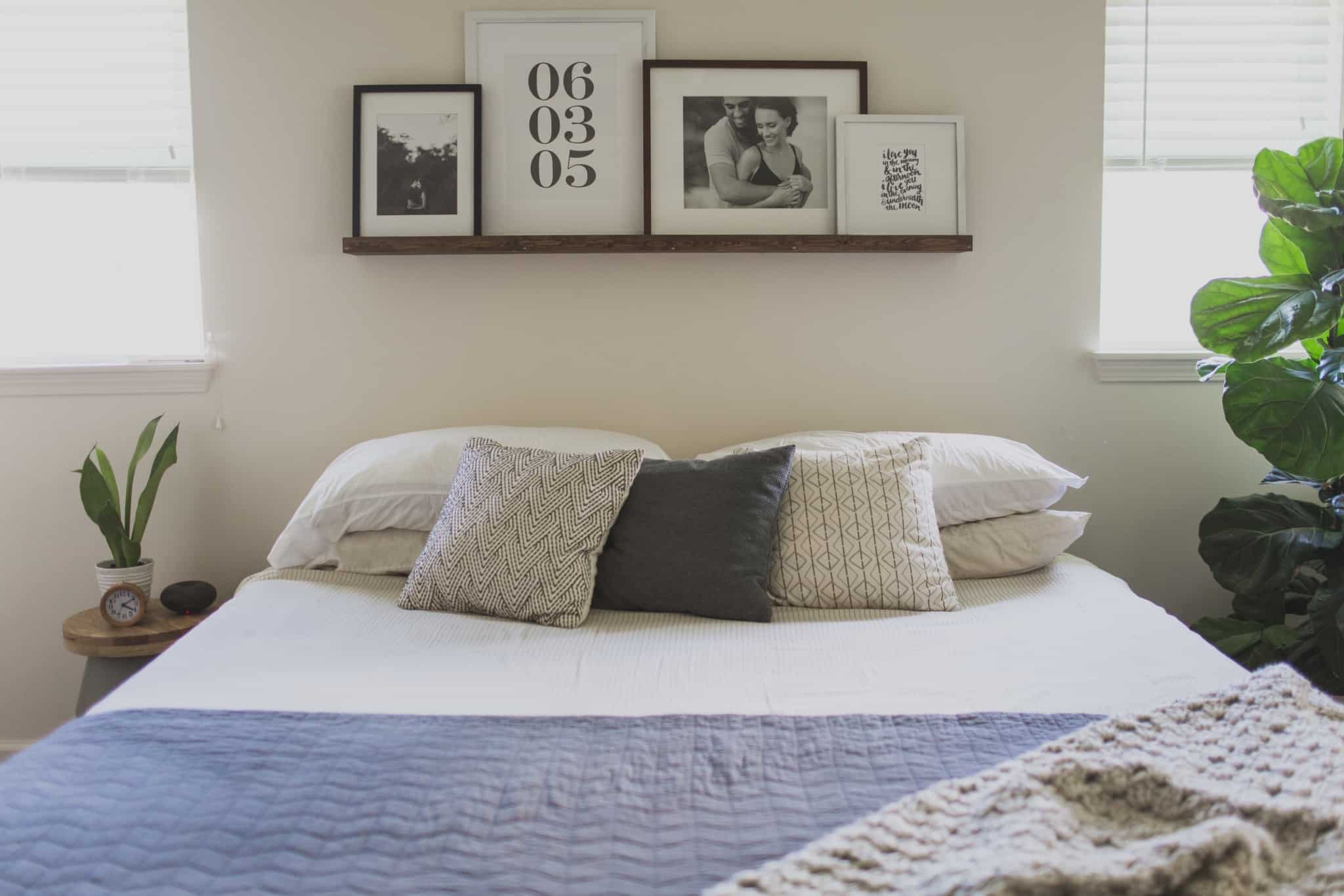 quarto com cama com três almofadas e molduras em cima