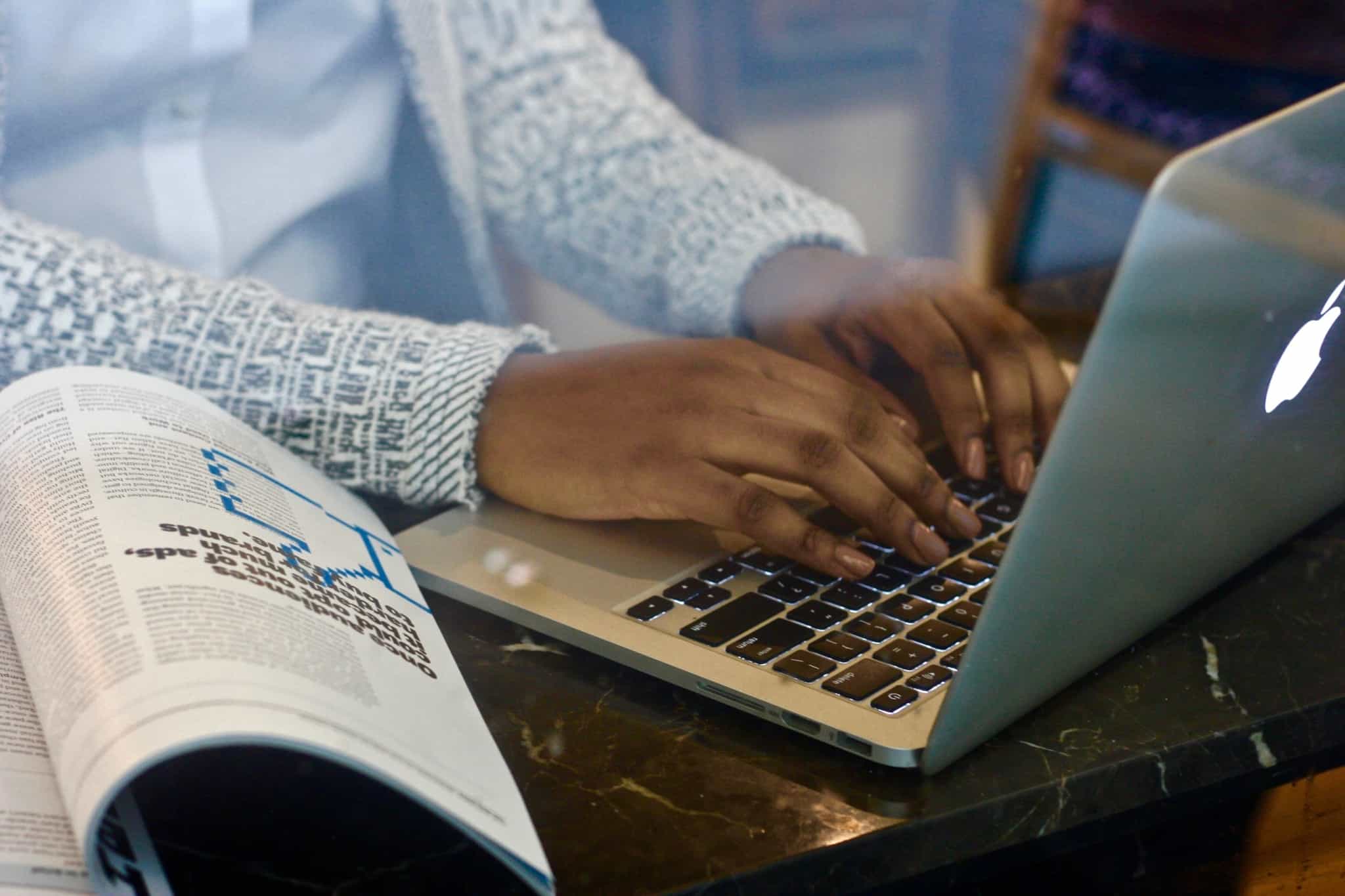 escrever no computador com uma revista aberta ao lado