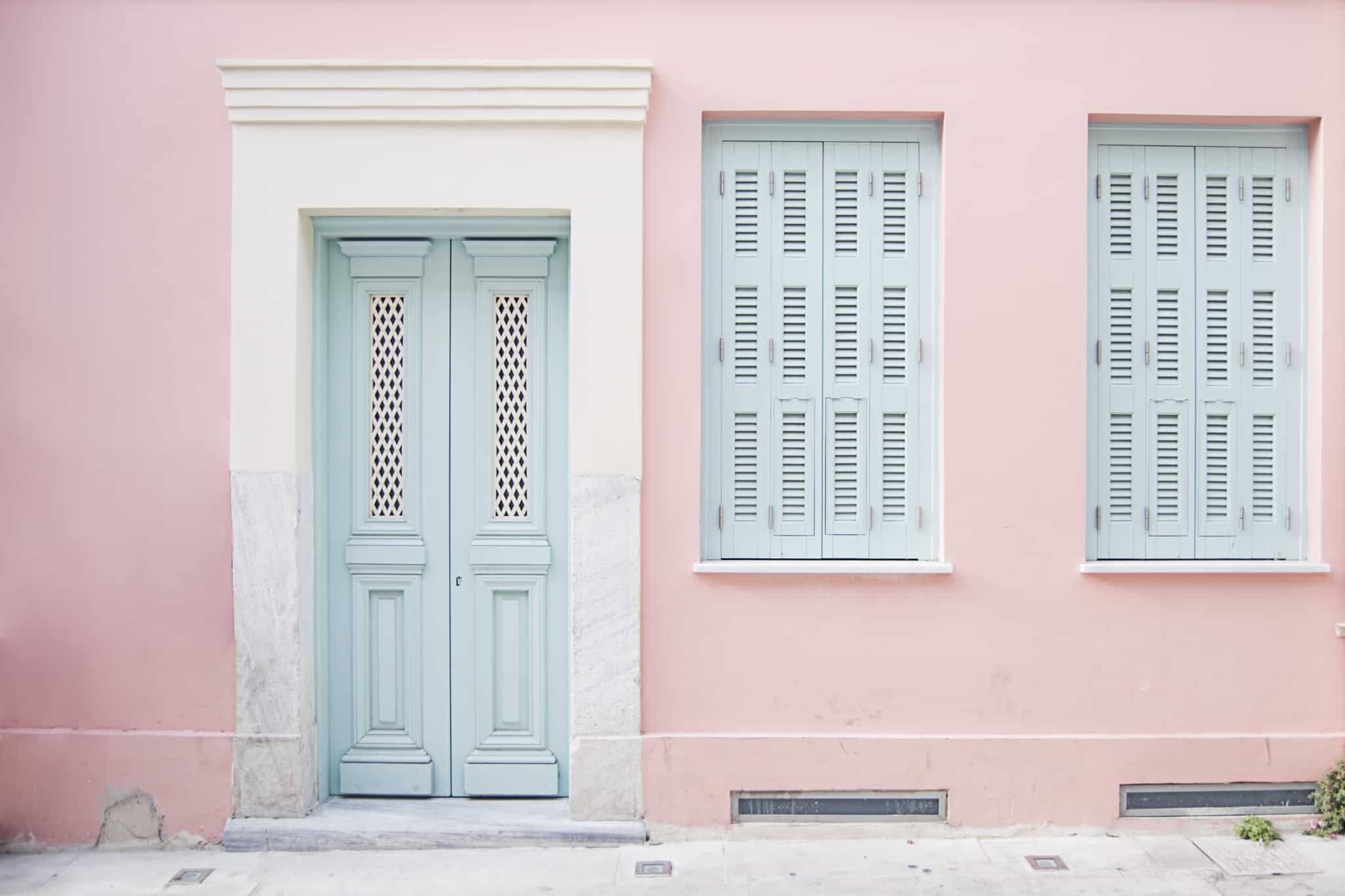 porta e duas janelas de uma casa cor de rosa