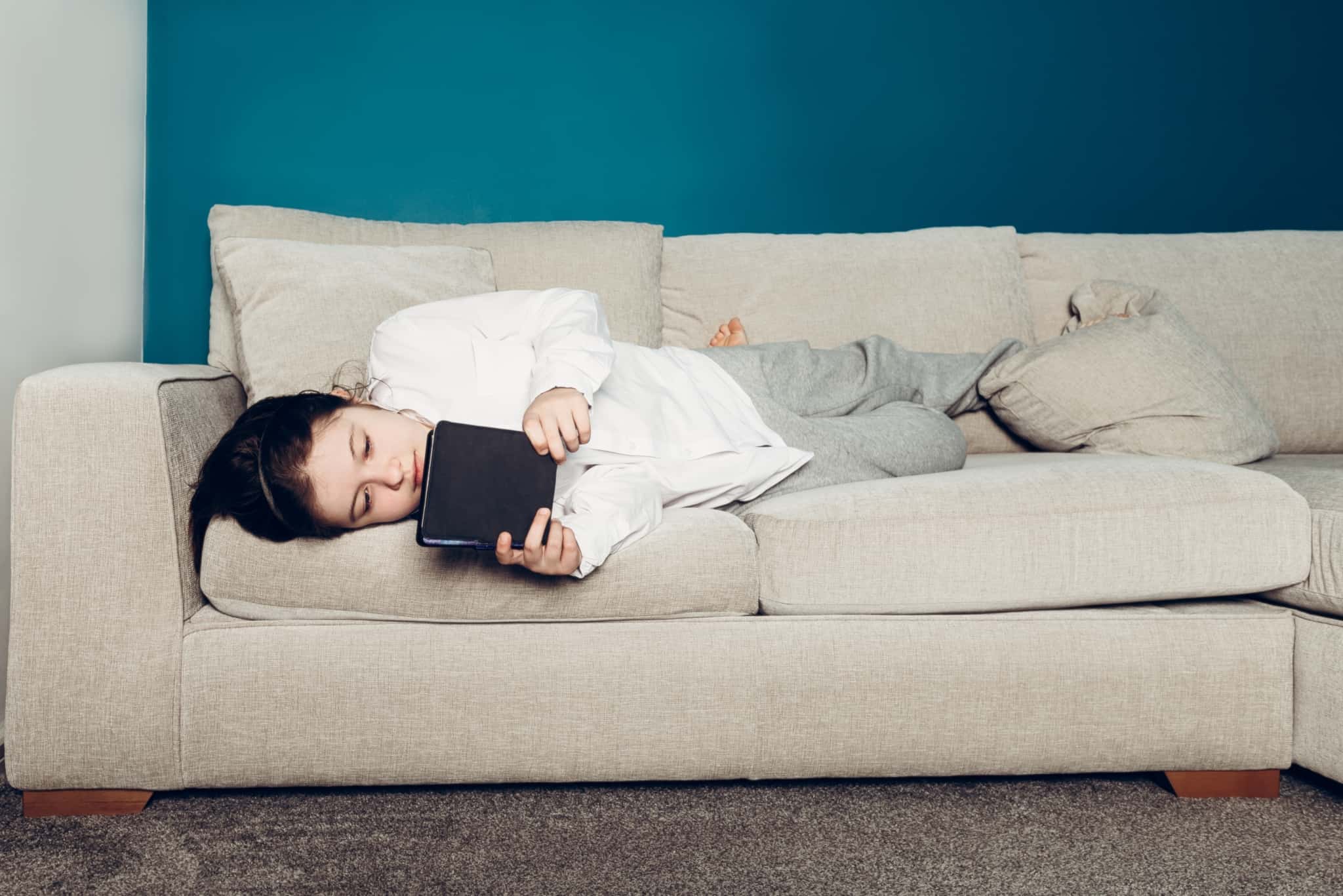 rapariga a ler um ebook deitada no sofá