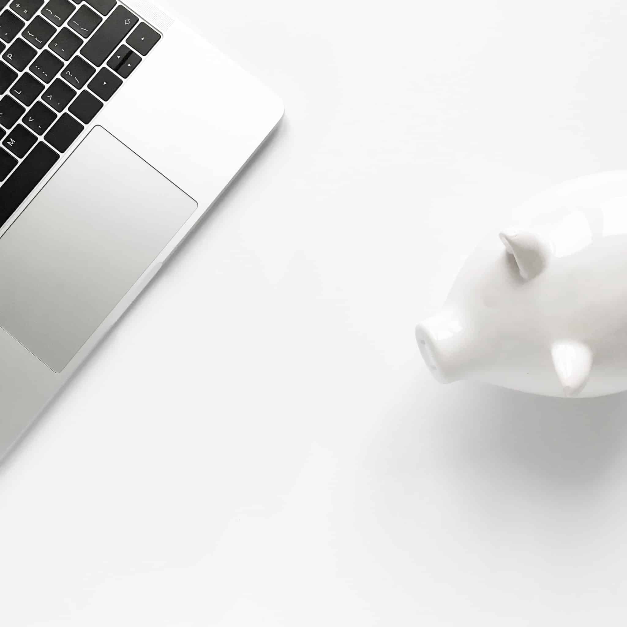 porquinho mealheiro branco e um computador