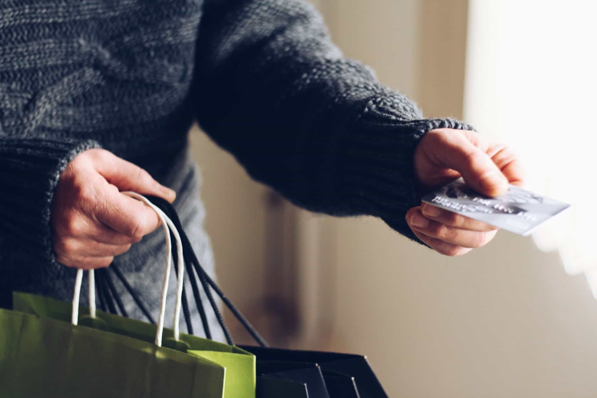 homem de camisola de lã escura a dar um cartão cinzento