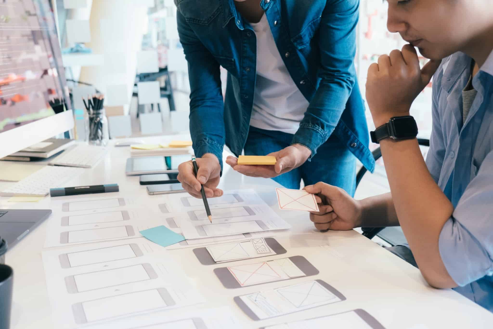 programadores trabalham em ux design com papeis em cima da secretária