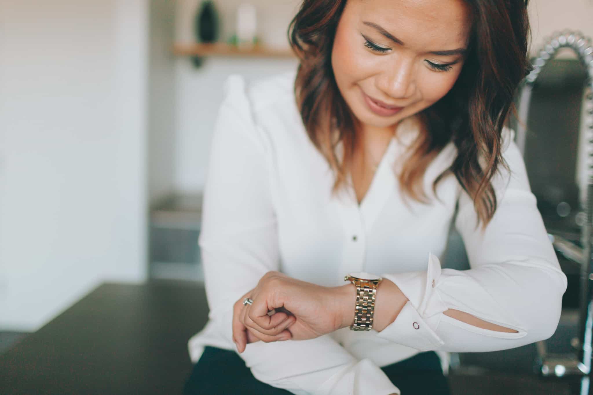 mulher a trabalhar a olhar para o relogio dourado no pulso
