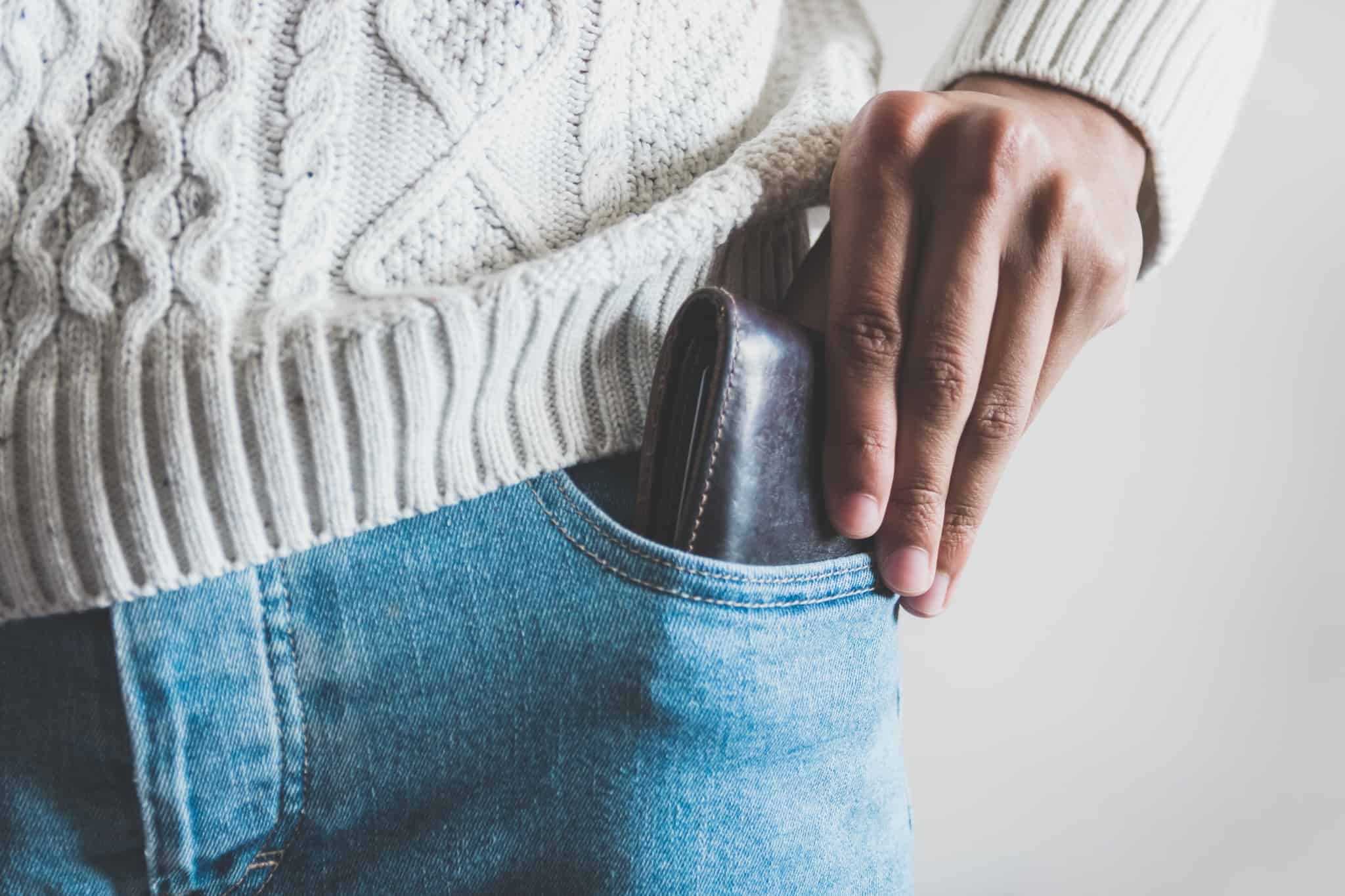 homem a retirar carteira em pele do bolso das calças de ganga