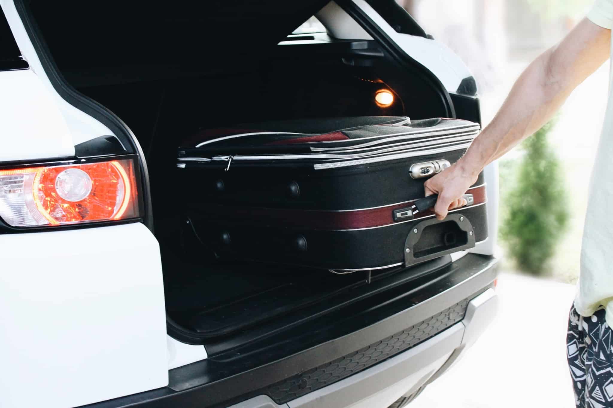pessoa a retirar mala de viagem da mala de um carro