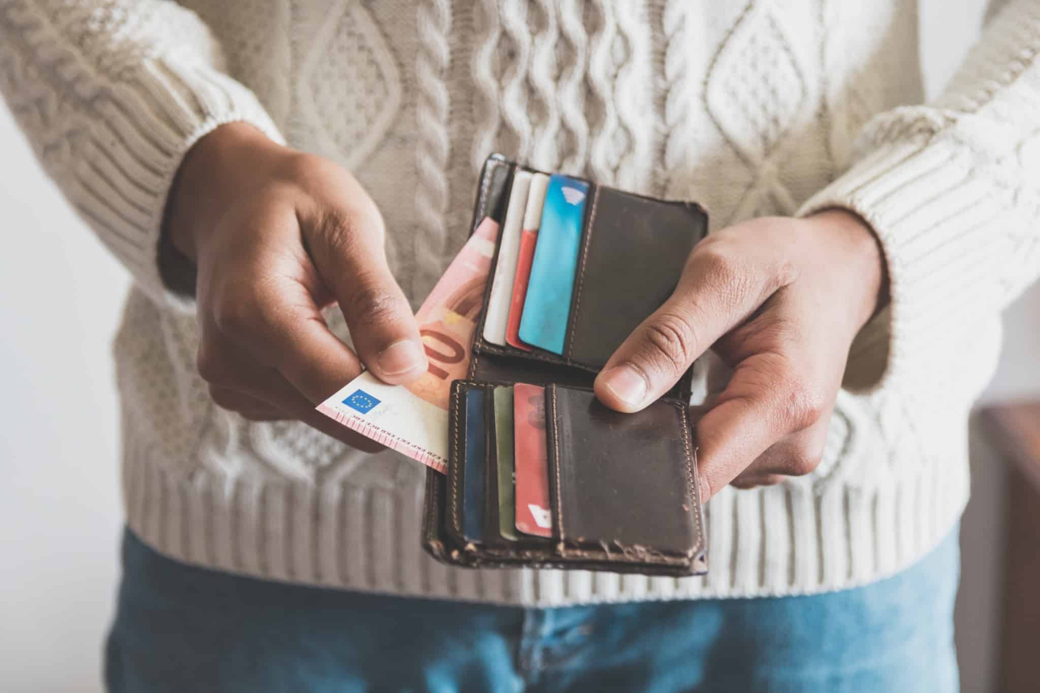 homem com uma carteira castanha a retirar uma nota de 10 euros