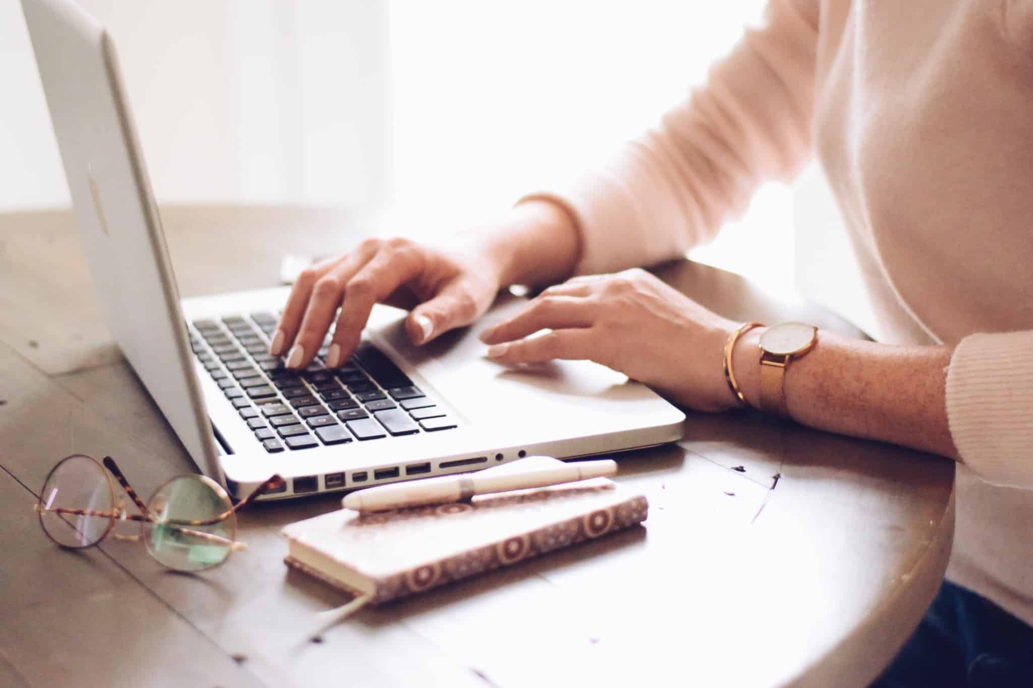 rapariga a mexer no portatil em cima da mesa