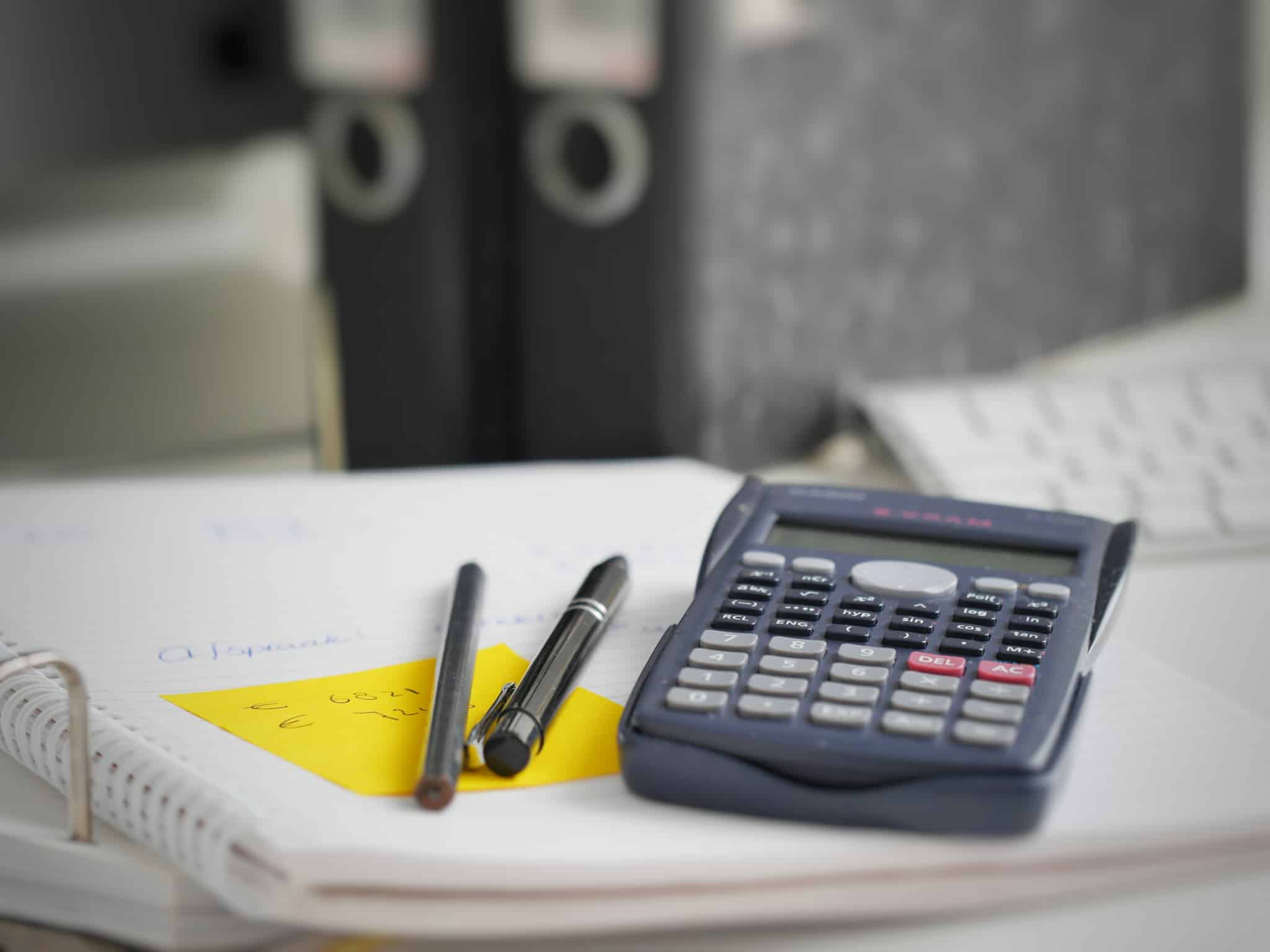 calculadora em cima de papeis de um dossier