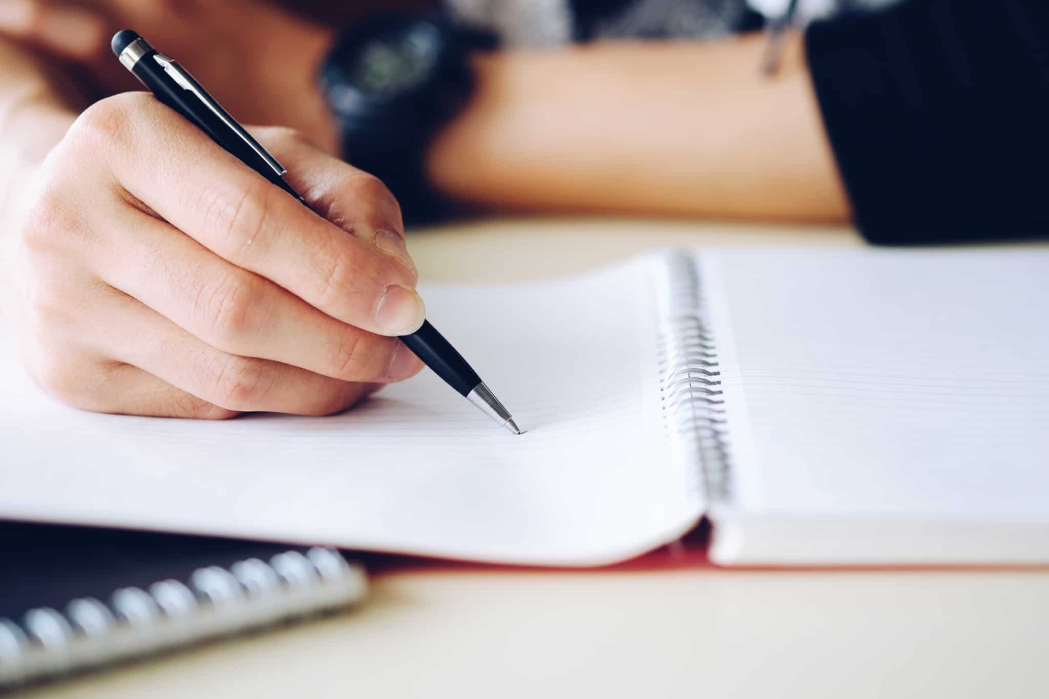 escrever com uma caneta num caderno de argolas