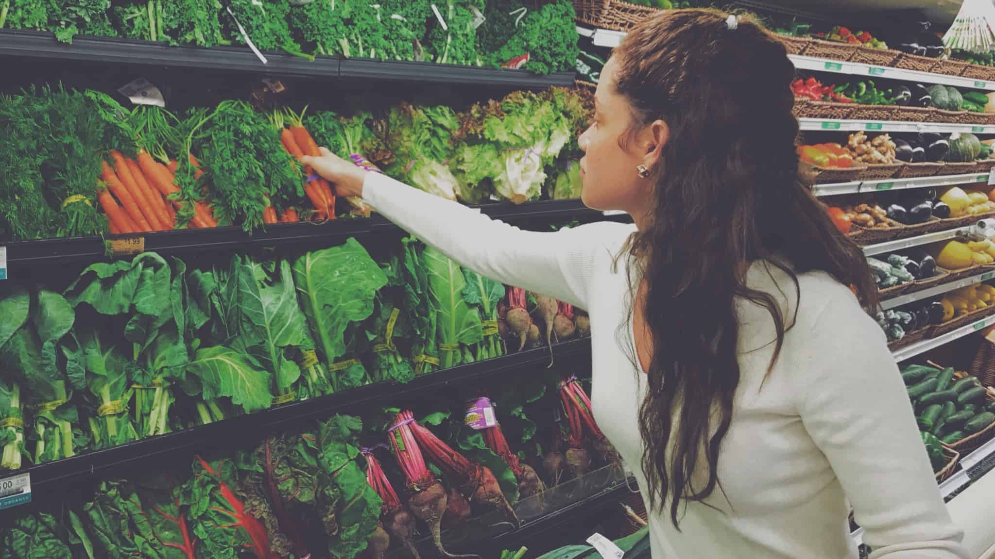 rapariga morena a escolher cenouras no supermercado